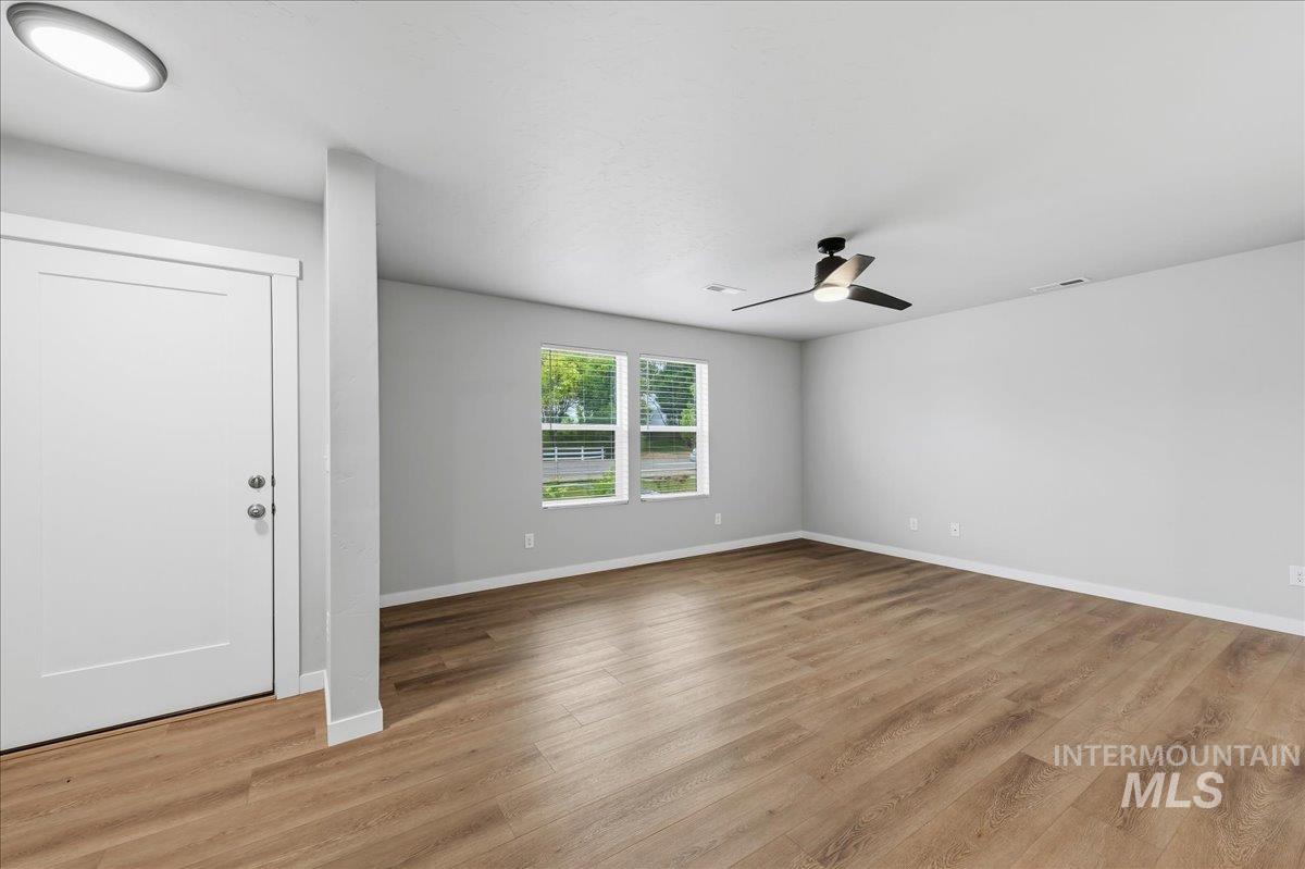 12475 West Victory Road Boise, ID 83709 - Photo 5 of 26 Spacious room featuring wood-finish flooring, light gray wall paint, and white trim