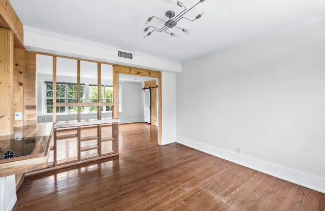 a view of an empty room with wooden floor and a window