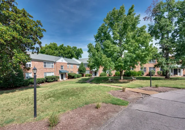 a view of a house with a big yard and large tree