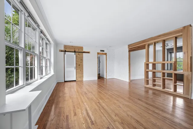 a view of an empty room with wooden floor and a window