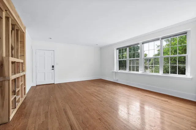 a view of an empty room with a window and wooden floor