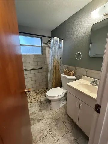 a bathroom with a granite countertop toilet a sink and a mirror
