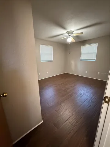 an empty room with wooden floor fan and windows