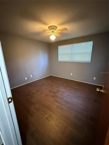 an empty room with a ceiling fan and wooden floor