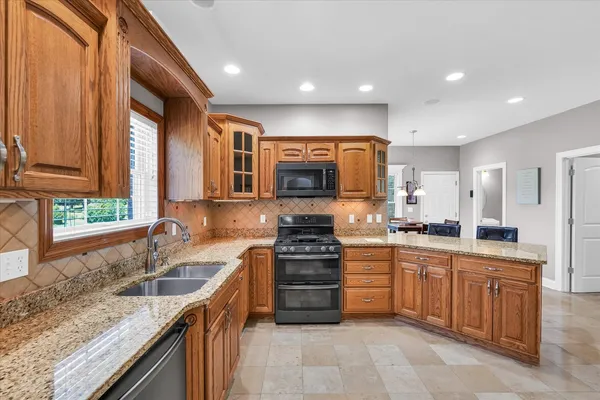 a kitchen with stainless steel appliances granite countertop wooden cabinets a sink and dishwasher a stove top oven with wooden floor