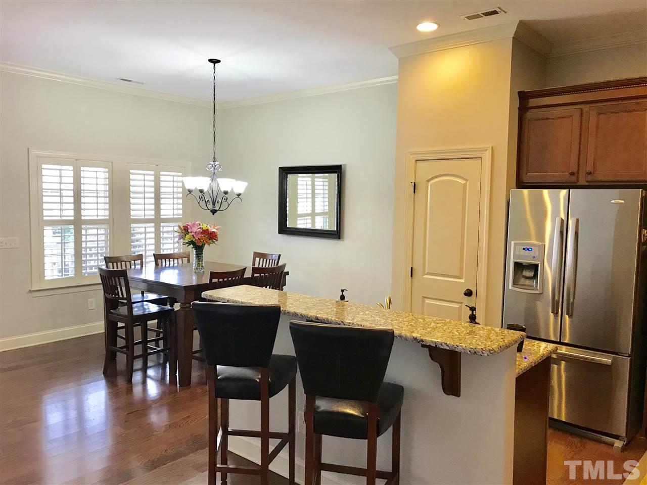 840 Historian Street Raleigh, NC 27603 - Photo 3 of 25 a kitchen with stainless steel appliances granite countertop dining table chairs and wooden floor