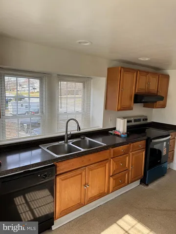 a kitchen with granite countertop a sink a stove and cabinets