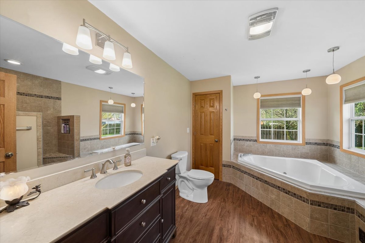 2 Division Street Bristol, IL 60512 - Photo 17 of 44 a bathroom with a granite countertop sink a large mirror a bathtub and a toilet