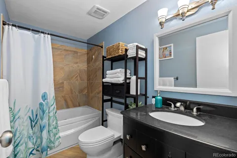 a bathroom with a granite countertop sink toilet a mirror and shower