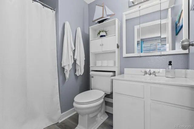 a bathroom with a granite countertop toilet sink and mirror