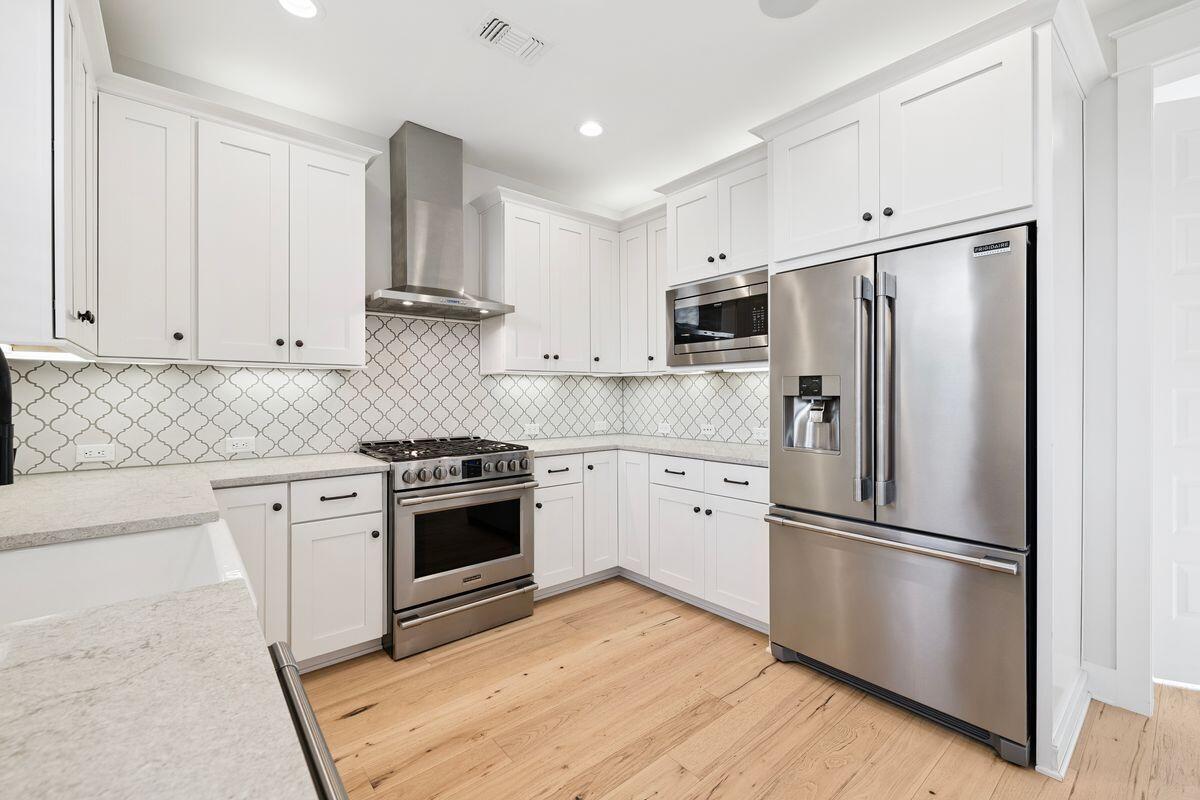 414 Ridgewalk Circle Santa Rosa Beach, FL 32459 - Photo 7 of 47 a kitchen with stainless steel appliances white cabinets and wooden floor