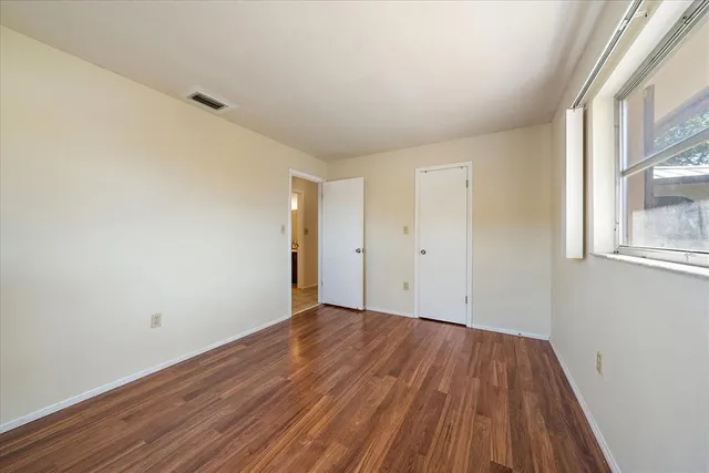 a view of an empty room with wooden floor and a window