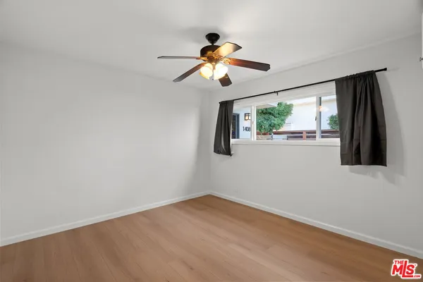 a view of empty room with wooden floor and fan
