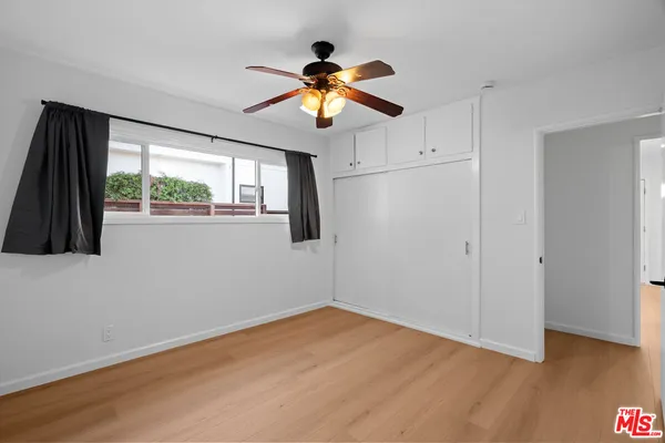 a view of empty room with wooden floor and fan