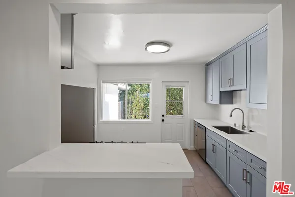 a kitchen with stainless steel appliances a sink a stove a refrigerator a window