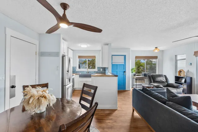 a living room with furniture kitchen view and a wooden floor