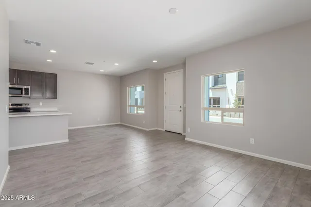 a view of an empty room with window and wooden floor