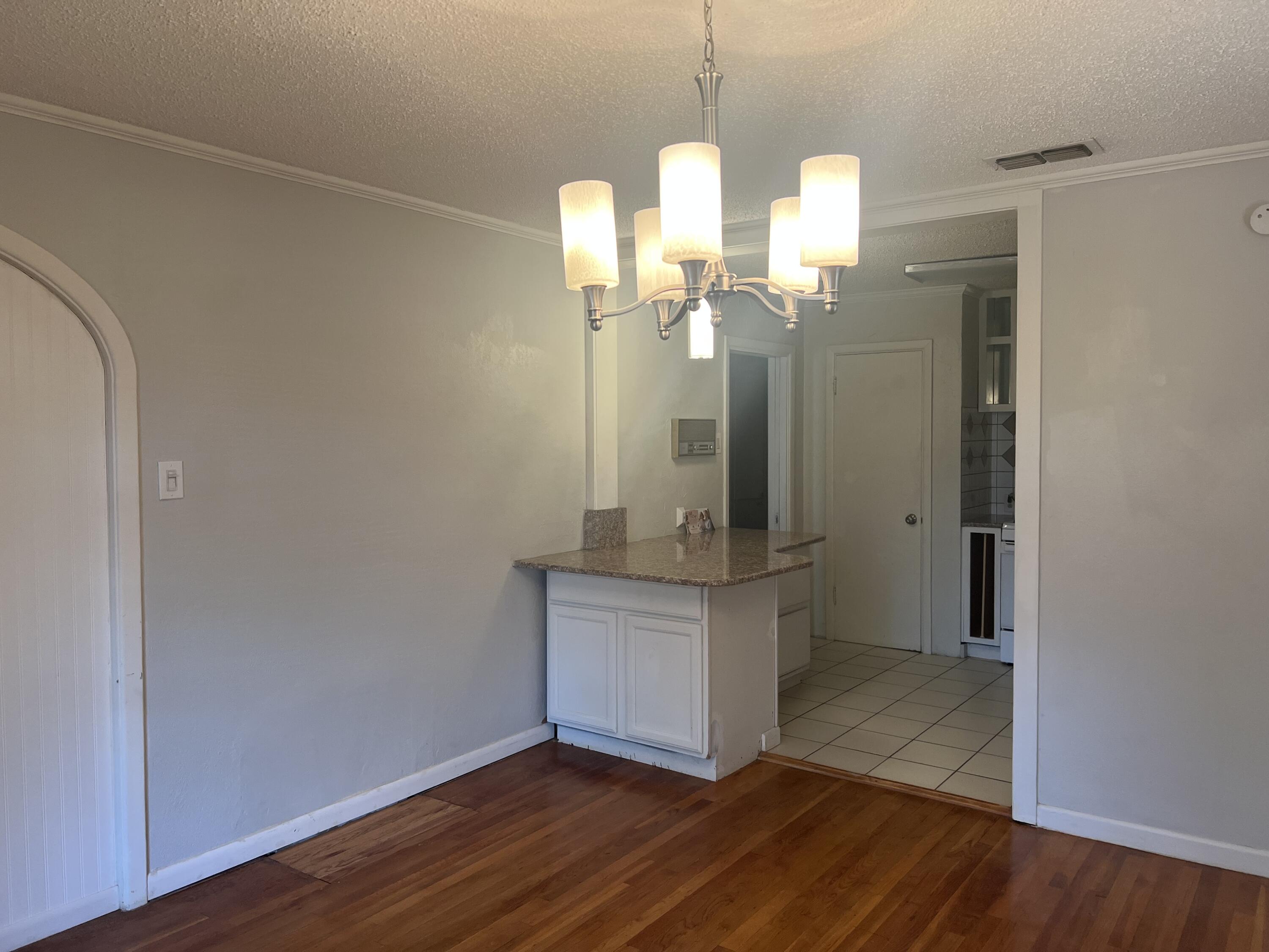 2424 33rd Street Lubbock, TX 79411 - Photo 14 of 23 a view of a kitchen with a wooden floor and a chandelier