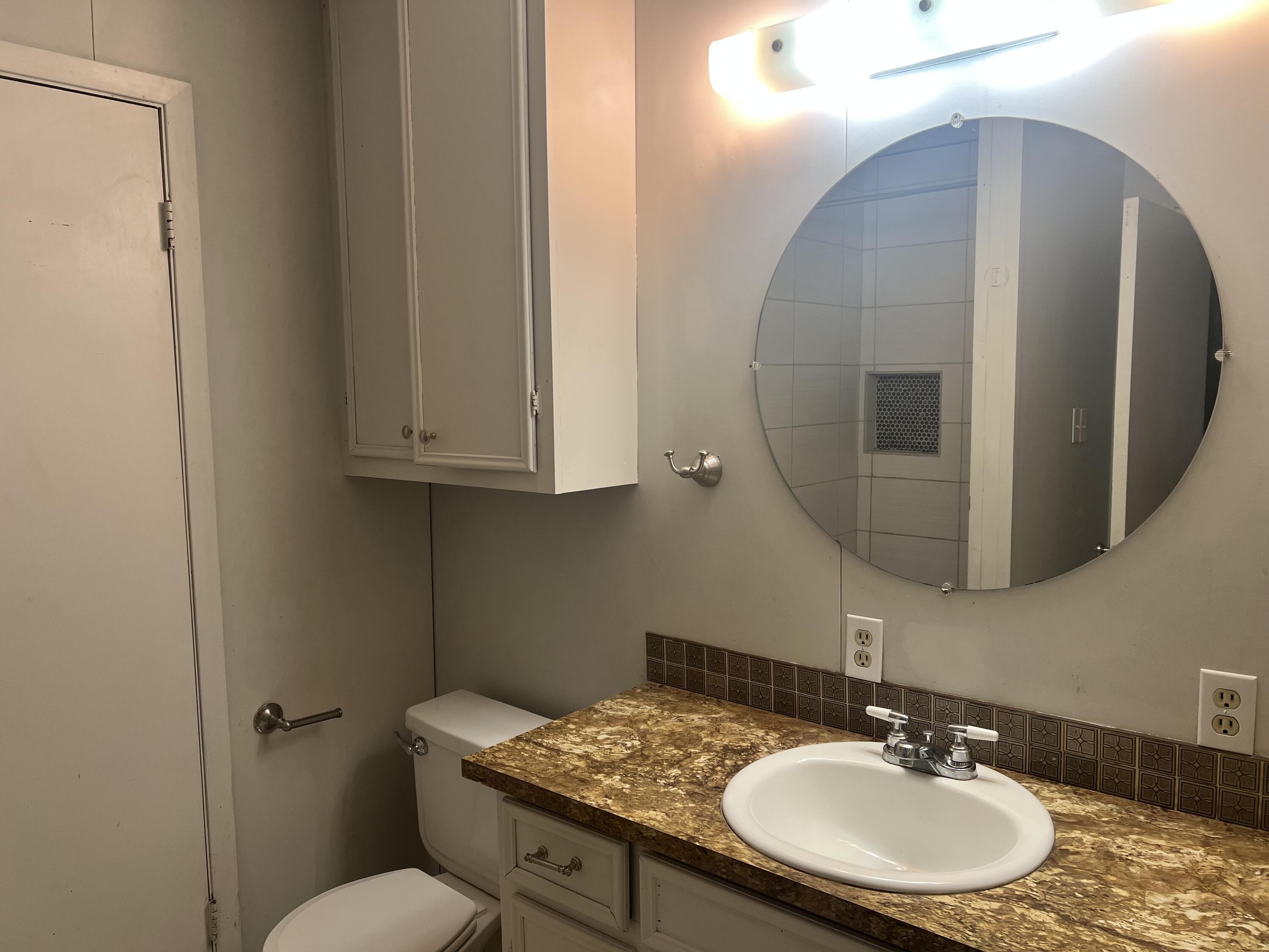 2424 33rd Street Lubbock, TX 79411 - Photo 16 of 23 a bathroom with a sink a toilet and a mirror