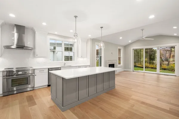 a large kitchen with stainless steel appliances granite countertop a stove and a wooden floors