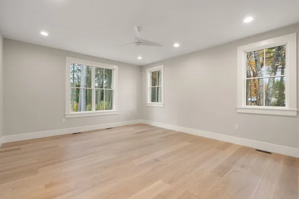 a view of an empty room with wooden floor and windows