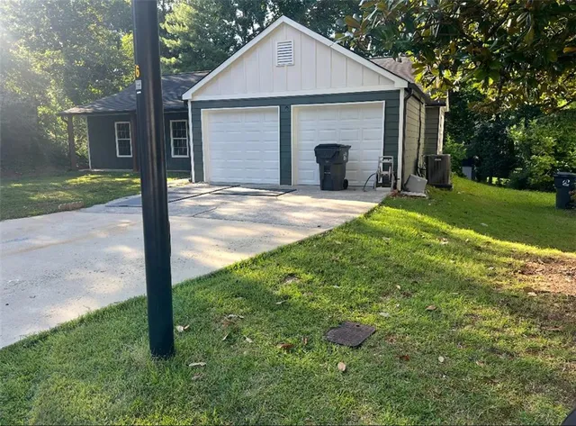 a view of a yard in front of a house with plants and large tree