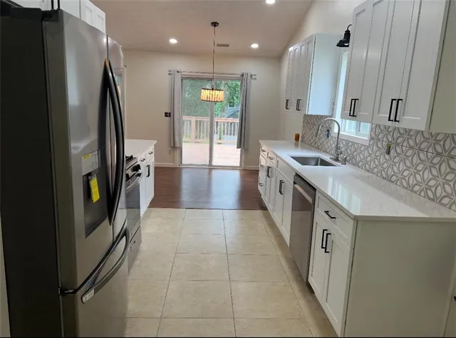 a large kitchen with stainless steel appliances granite countertop a refrigerator and a sink