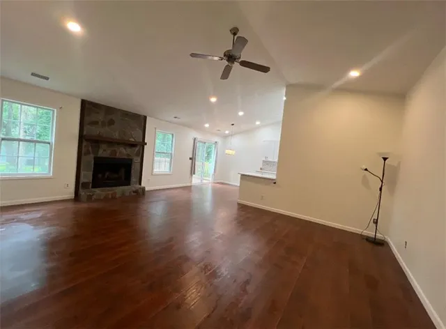 an empty room with wooden floor fireplace and windows