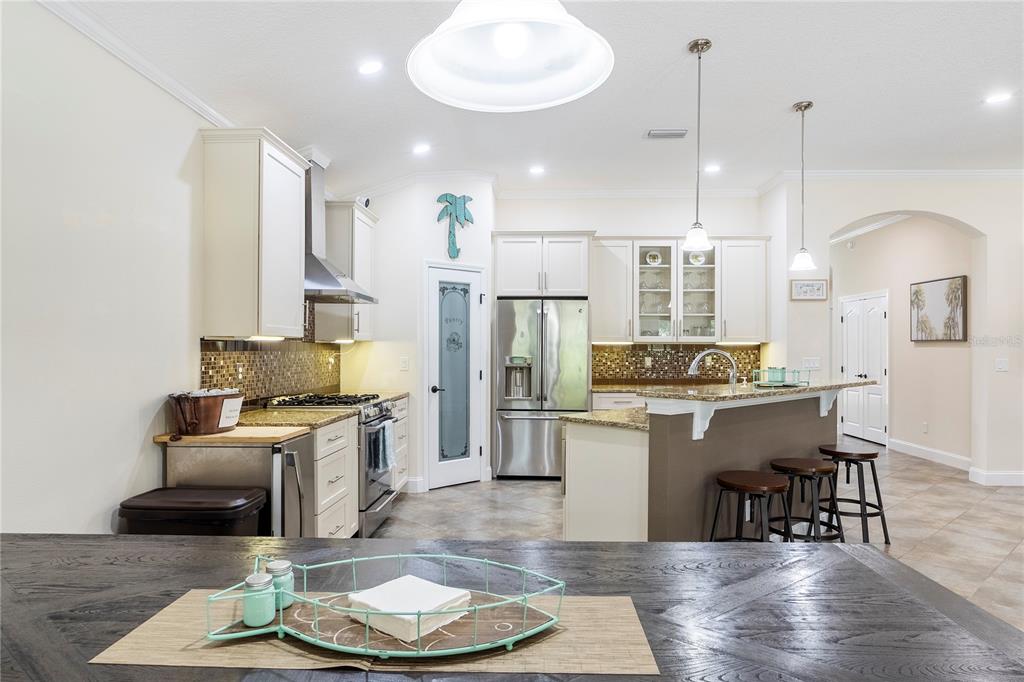 265 Pinehurst Pointe Drive St. Augustine, FL 32092 - Photo 22 of 66 a kitchen with stainless steel appliances granite countertop a refrigerator a stove a sink dishwasher a dining table and chairs with wooden floor