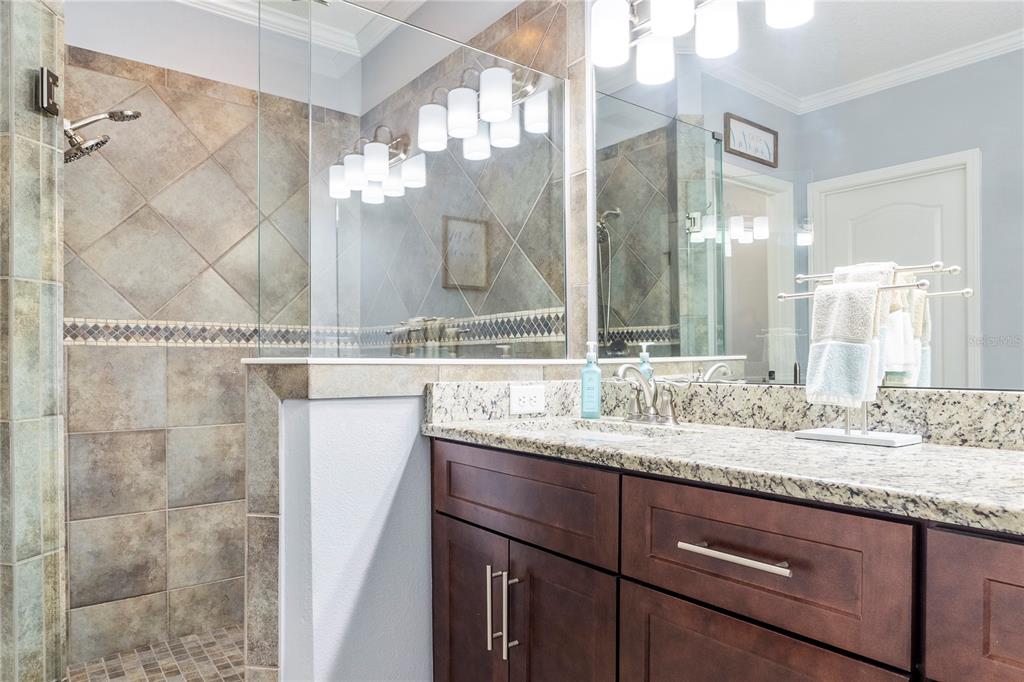 265 Pinehurst Pointe Drive St. Augustine, FL 32092 - Photo 37 of 66 a bathroom with a granite countertop sink a mirror and a shower
