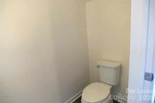 a white toilet sitting next to a white wall