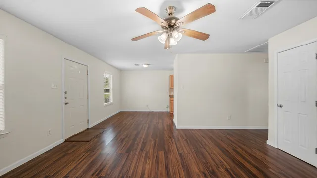 an empty room with wooden floor and windows