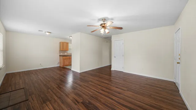 an empty room with wooden floor and ceiling fan