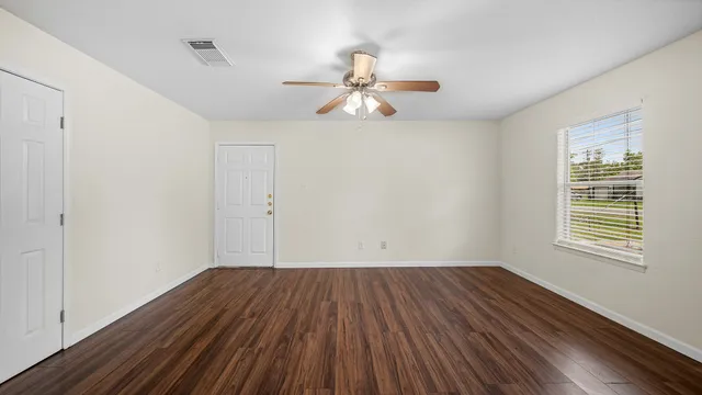a view of empty room with wooden floor and fan