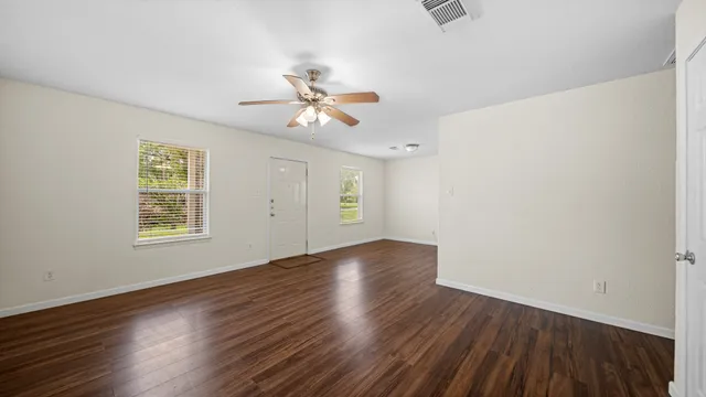 a view of an empty room with wooden floor and a window