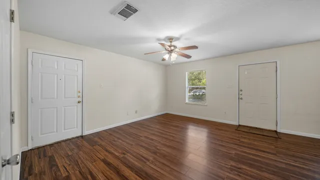 an empty room with wooden floor and windows
