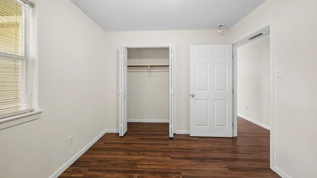 a view of an empty room with wooden floor and a window
