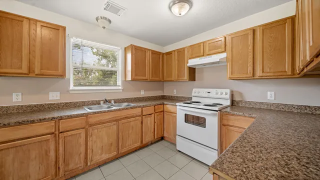 a kitchen with granite countertop cabinets sink and window