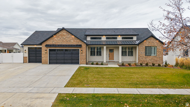 897 North Main Street Mapleton, UT 84664 - Photo 1 of 1 View of front of home featuring a porch, a standing seam roof, driveway, an attached garage, and brick siding