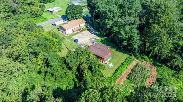 an aerial view of residential house with outdoor space and trees all around