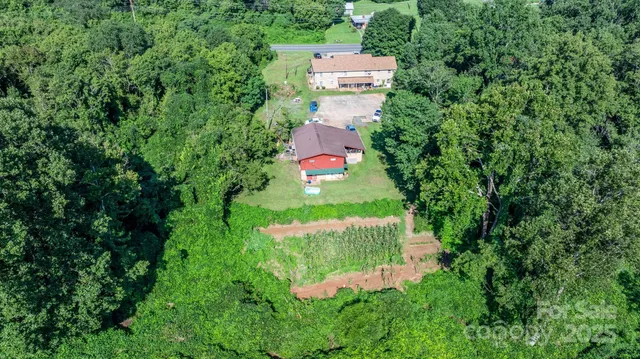 an aerial view of residential house with outdoor space and trees all around