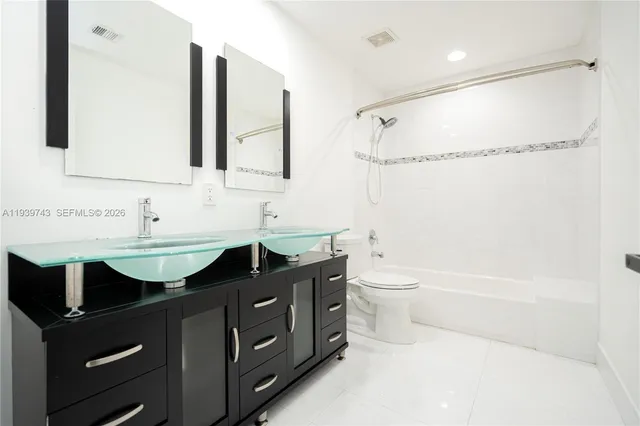 a bathroom with a double vanity sink toilet mirror and bathtub