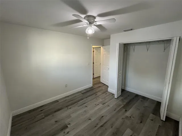 an empty room with wooden floor and fan
