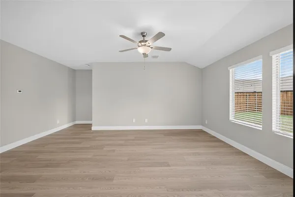 a view of an empty room with window and wooden floor