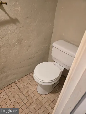 a white toilet sitting next to a white wall