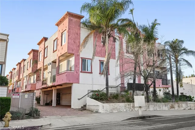 a view of a white building among the street and palm trees