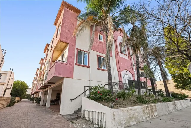 a front view of multiple houses with palm trees