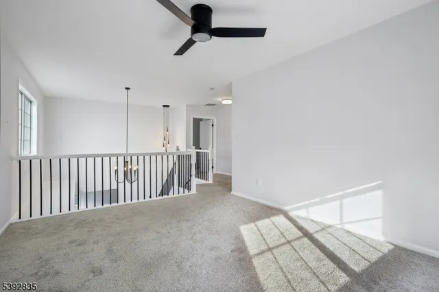 an empty room with ceiling fan and windows