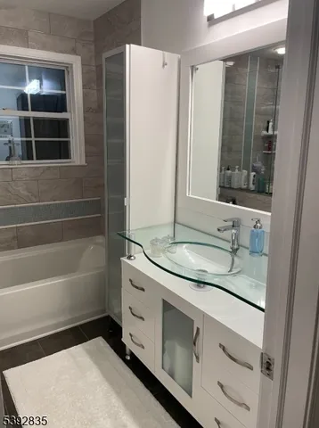 a bathroom with a granite countertop sink a mirror and a bathtub