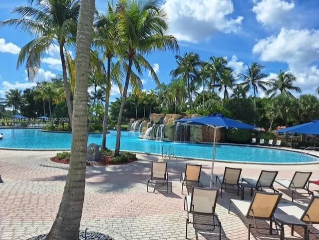 a patio with a table and chairs under an umbrella with palm trees